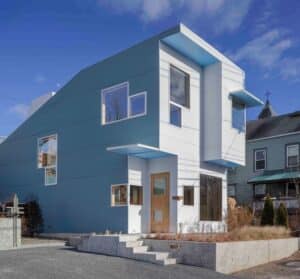 L-shaped house façade clad in corrugated aluminum reflecting sunlight