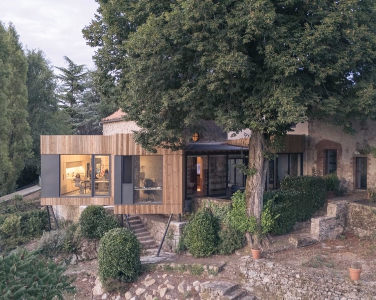 Exterior view of Clos Saint-Martin project blending historical stone buildings with modern wooden extensions and landscaped terraces.