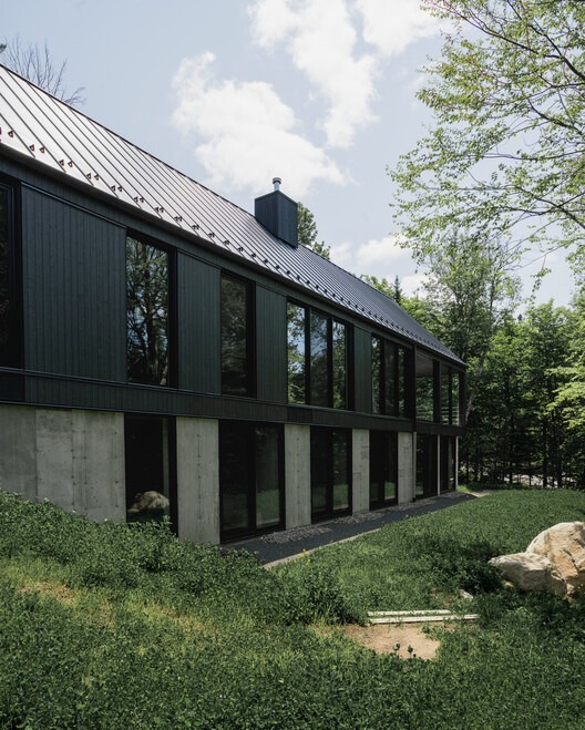 Residential building in Laurentians integrated with surrounding nature and interior spaces.