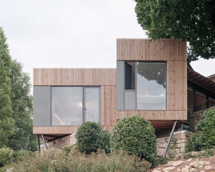 Exterior view of Clos Saint-Martin project blending historical stone buildings with modern wooden extensions and landscaped terraces.
