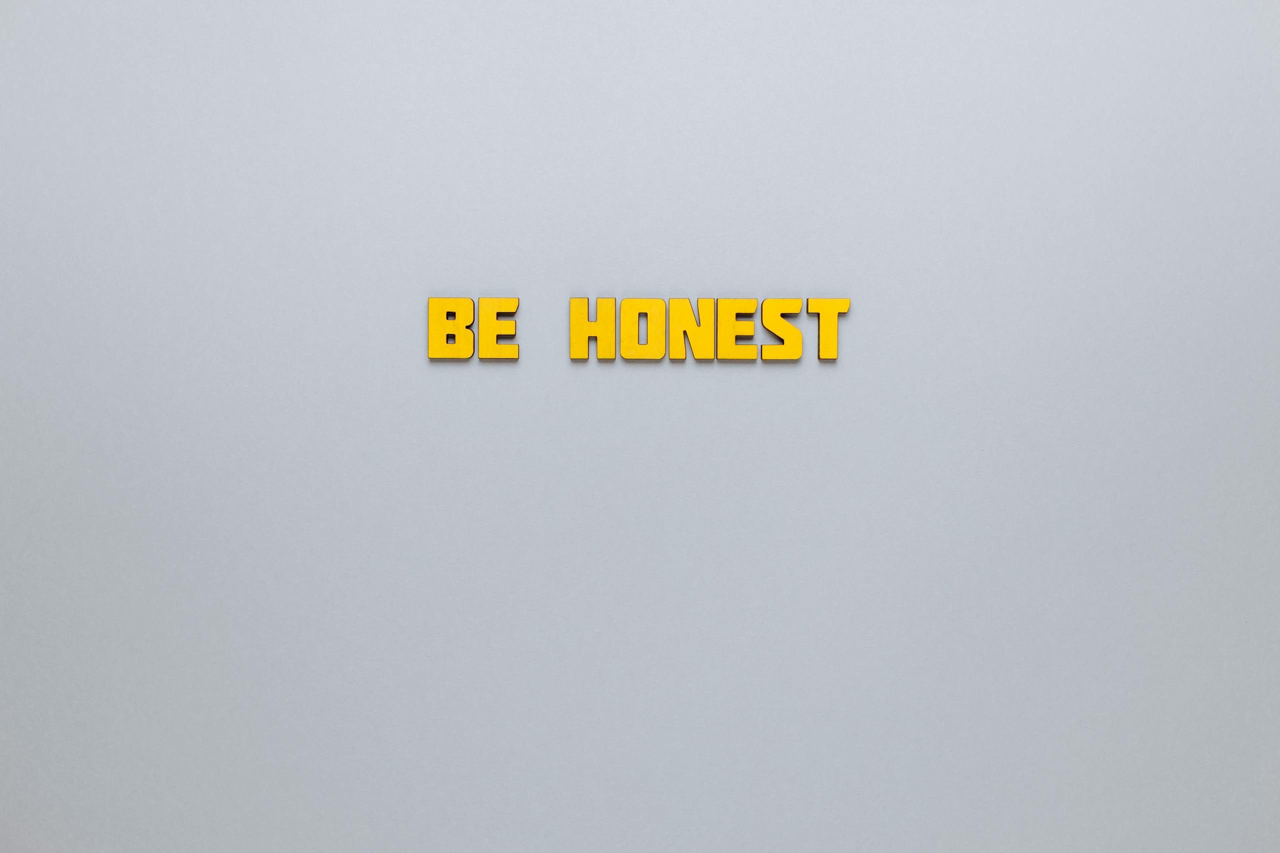 Simple yellow text 'Be Honest' on a neutral background, emphasizing clarity and inspiration.