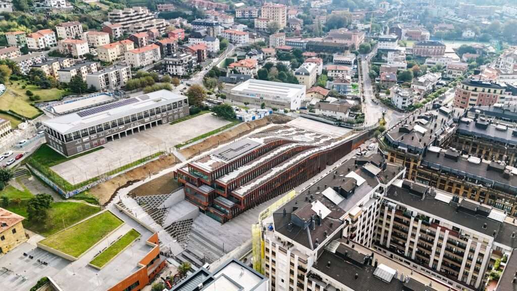 Aerial view of a modern building with a flowing architectural design blending seamlessly into the urban fabric.