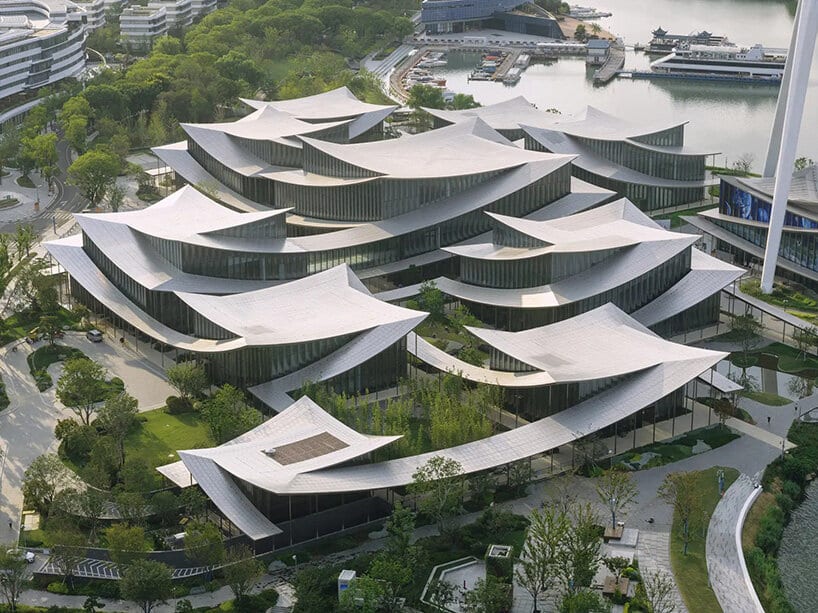 Exterior view of Suzhou Museum of Contemporary Art showing the ribbon-like undulating roof and interconnected pavilions over Jinji Lake.