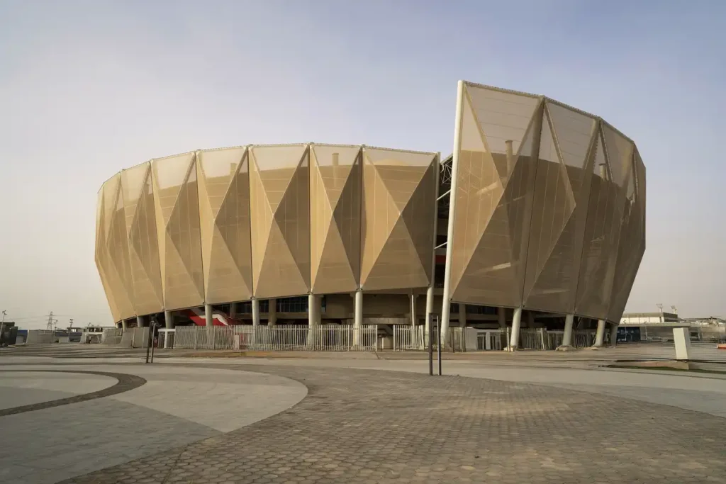 Textile facade filters desert light, blending architecture with the arid horizon.