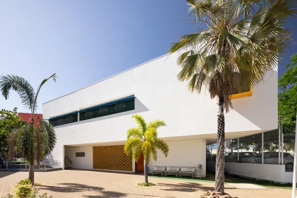 واجهة بيضاء ناصعة تحت شمس قوية، تبرز جمالية التظليل والتهوية الطبيعية.