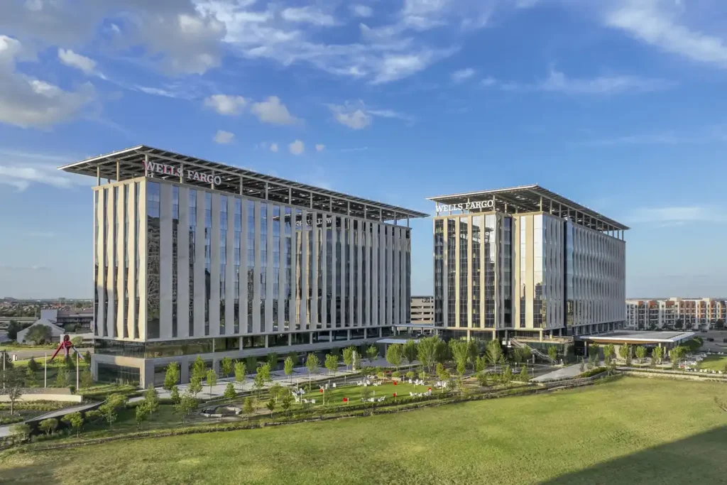 أبراج زجاجية تندمج مع السماء، وتحيط بها حديقة خضراء هادئة.