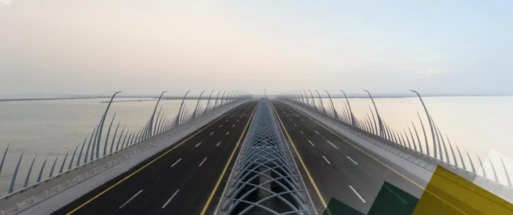 A vanishing-point highway over calm waters, steel curves whispering motion and serenity at dawn&rsquo;s soft glow.