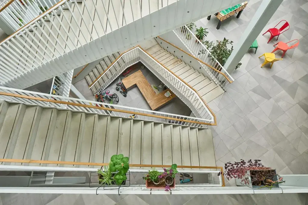 Facade of a residential building in Ludlstra&szlig;e featuring large windows, staggered terraces, and front green areas.