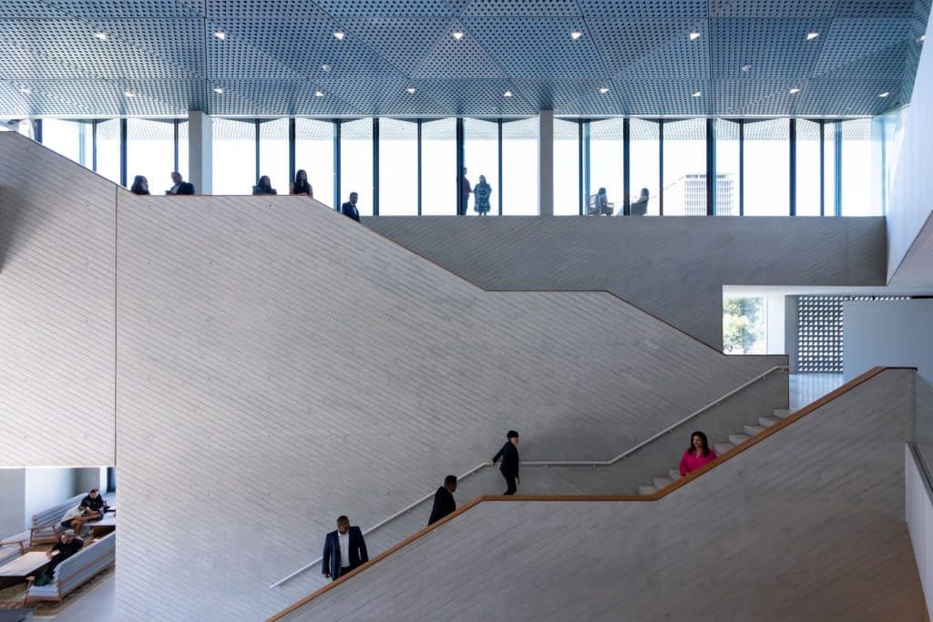 Wide wooden staircases connect levels at the Ismaili Center, where visitors move deliberately through a calm, ordered space.