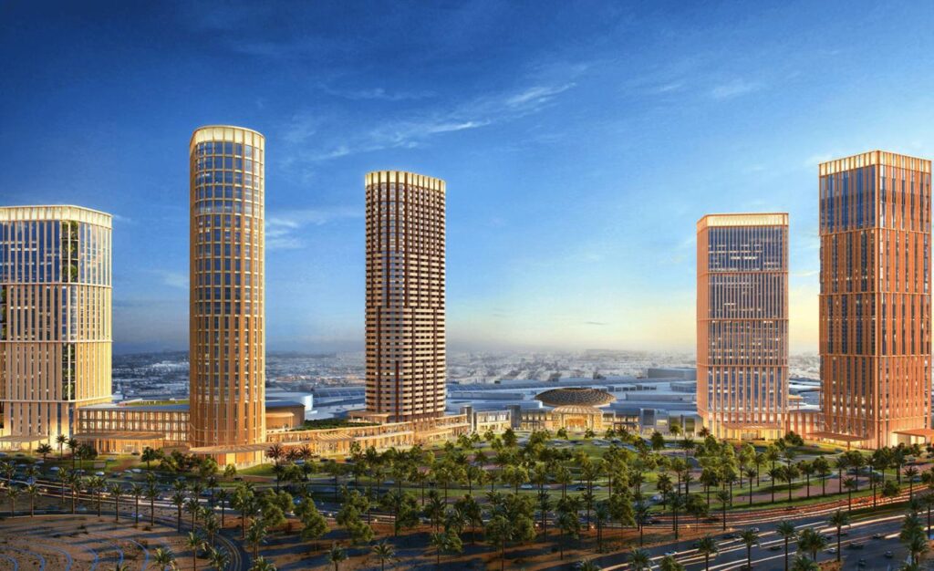 منظر شامل لمشروع ألافيونز الرياض، يجمع بين أبراج سكنية وفندقية ومركز تجاري، محاط بمساحات خضراء وطرق حديثة تحت سماء صافية.