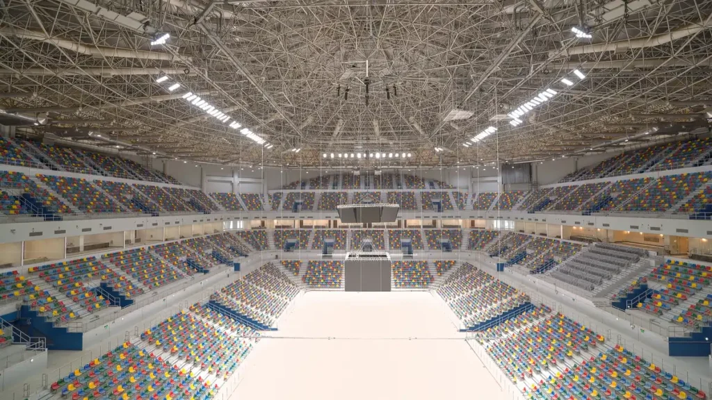 Vast column-free arena under a lightweight steel lattice roof, vibrant seats energize the space.