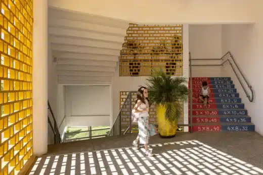 سلالم متدرجة بألوان حيوية ونمط دراسي، تضيئها ظلال حواجز كوبوغو المثقبة.