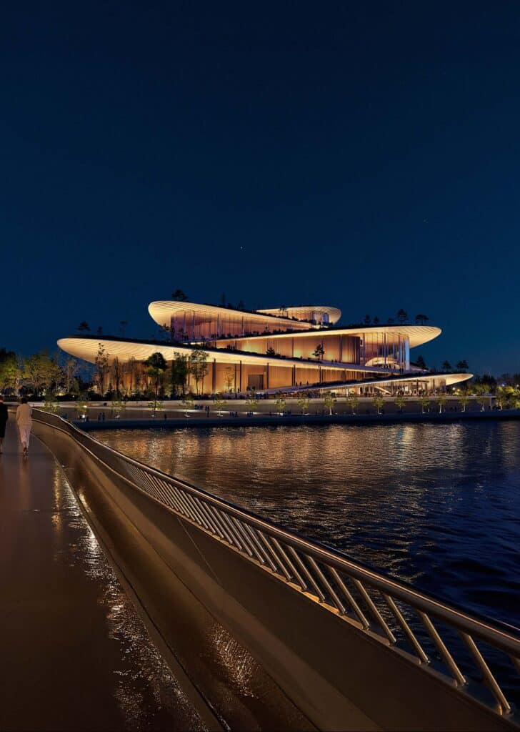 دار أوبرا هامبورغ مضاءة ليلاً، مع انعكاسات المبنى على المياه المحيطة.