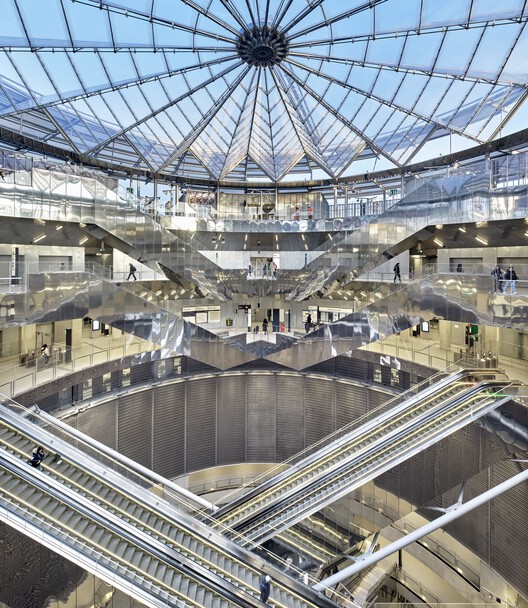 قبة زجاجية ضخمة تعلو فراغًا دائريًا يتدرج نحو الأعماق بإضاءة عمودية.