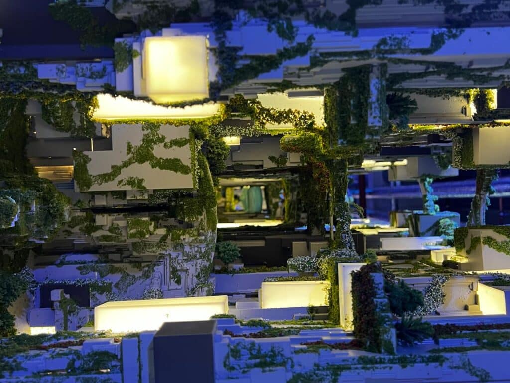 نموذج معماري لمشروع الخط ذا لاين يُظهر التصميم العمودي المغطى بالنباتات والإنارة الدافئة، يعكس تكامل الطبيعة مع الهندسة المستقبلية.