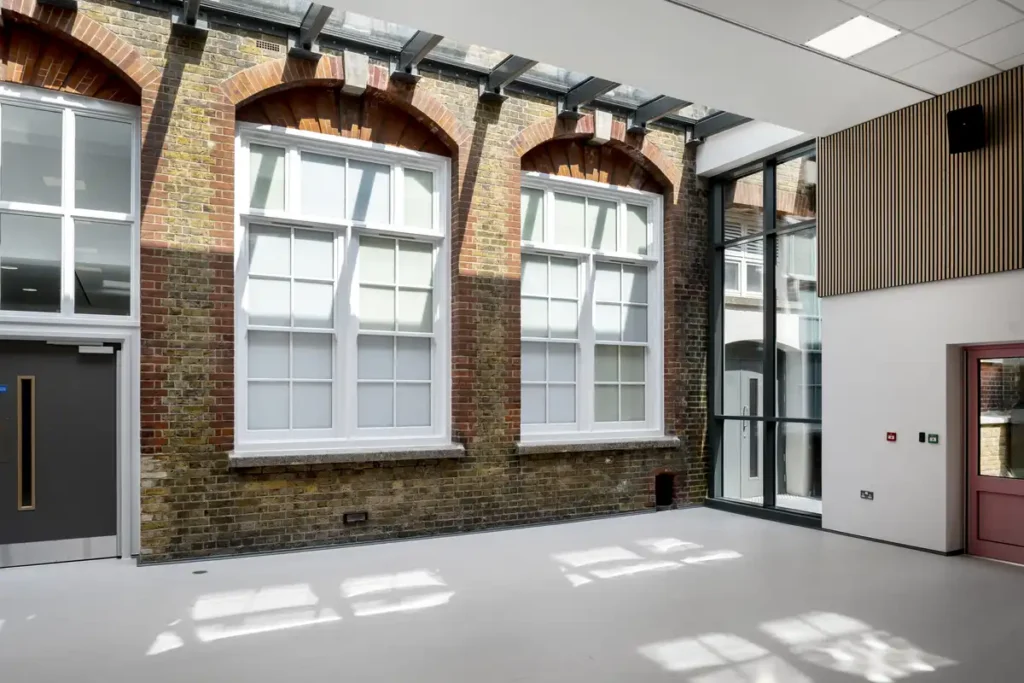 نوافذ زجاجية متدرجة تعكس الضوء على الفناء وتدمج المبنى بالحديقة