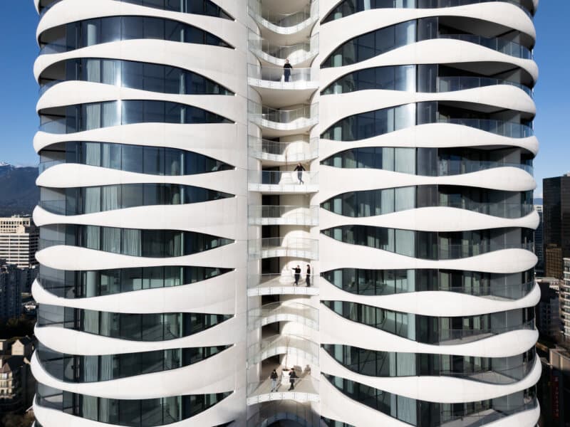 واجهة برج مقسومة، شرفات متموجة بيضاء، حدائق سماوية عمودية، تفاعل سكني.