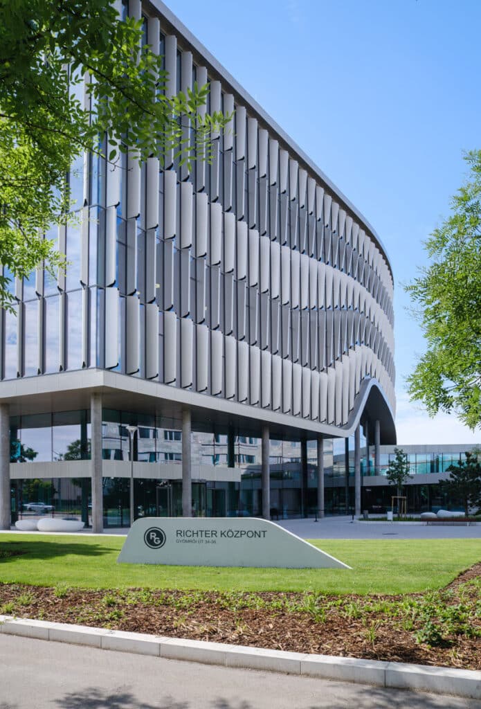 مبنى حديث يرتفع بين الأشجار الخضراء تحت سماء صافية ومشمسة.