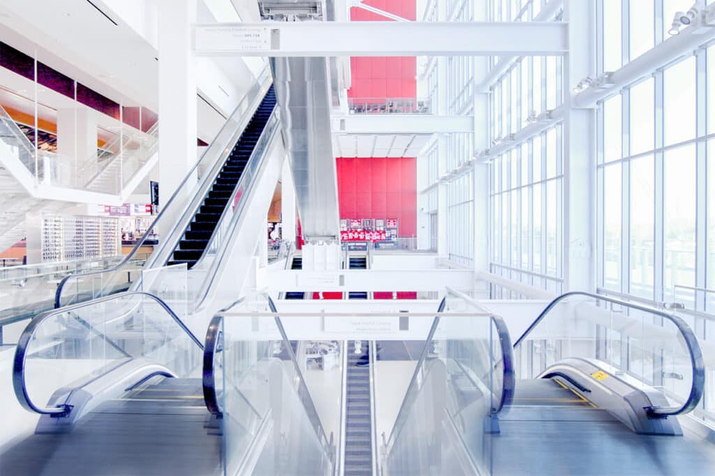 ممرات داخلية في ملعب ليفي بتصميم نظيف وحديث، مع سلالم كهربائية زجاجية وأعمدة بيضاء وإضاءة طبيعية واسعة.