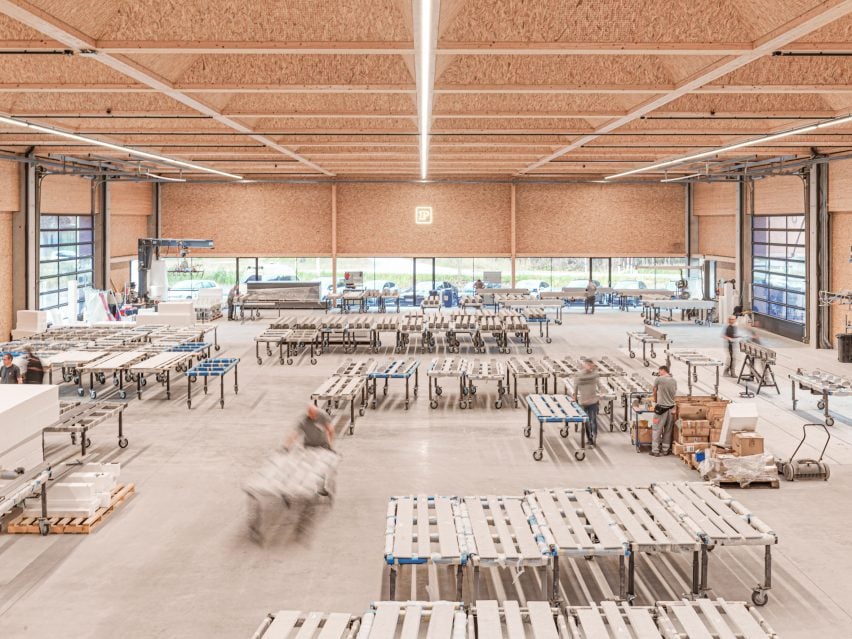 Spacious timber ceilinged production hall in Austria, with mobile workstations and warm natural light flooding the industrial floor.