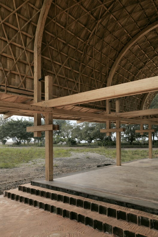 Side view of the pavilion showing the interplay of natural materials such as volcanic stone and clay tiles with bamboo.