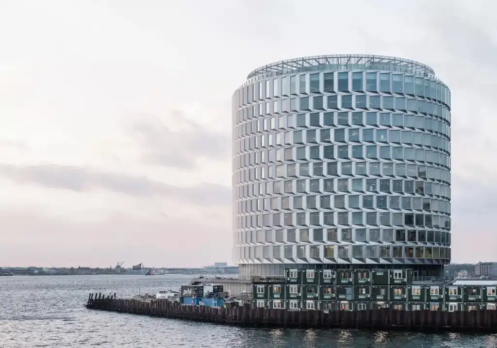 قمة نوردو الأسطواني يطل على الميناء في وقت الغروب، مع انعكاسات خفيفة على الماء وأبنية صناعية في الخلفية.