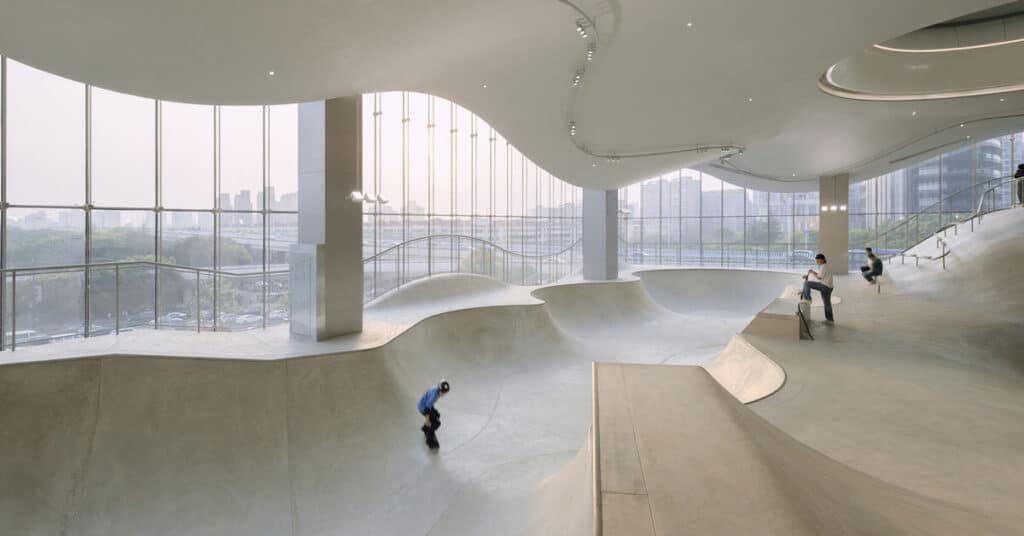Panoramic glass facade of the indoor skatepark in Shanghai, revealing undulating bowls and dynamic curves.