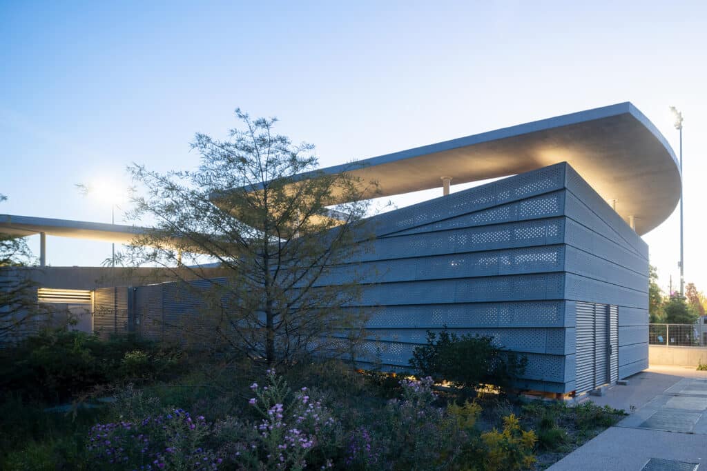 واجهة خرسانية مثقبة تعكس الضوء على سطح الجناح المطل على النهر.