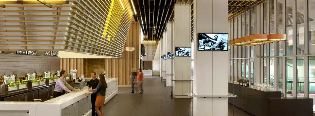 ممر داخلي أنيق في ملعب ليفي، بسقف خشبي مضاء، وبارات جانبية، وشاشات عرض على الجدران، وضيوف يتفاعلون في جو حديث.