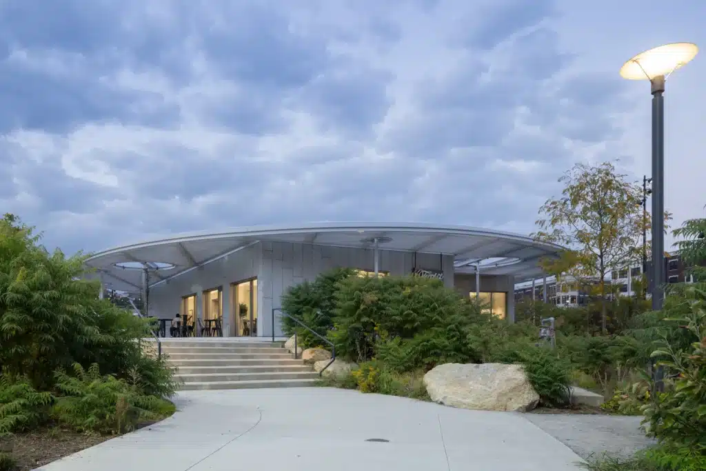 منظر الغروب على جناح غانسيفورت يُظهر الإضاءة الدافئة تنبعث من داخله نحو الواجهة الخرسانية.