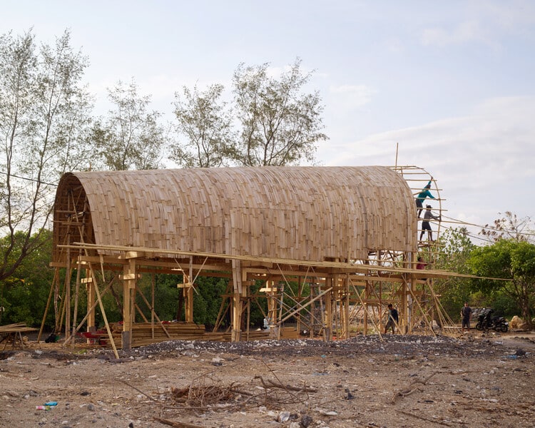 Side view of the pavilion showing the interplay of natural materials such as volcanic stone and clay tiles with bamboo.