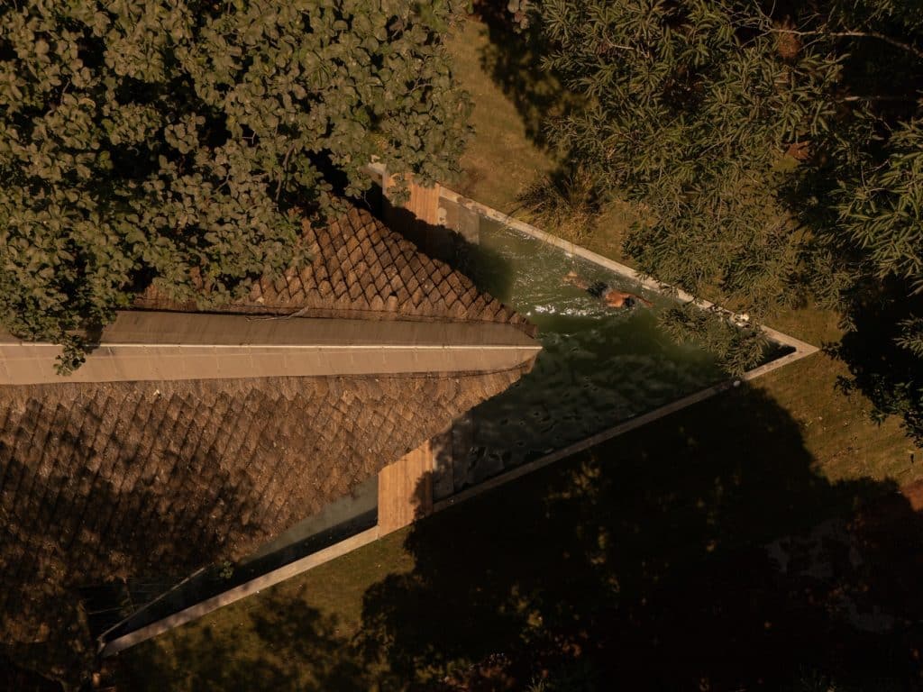 Interior view of the central living space under the oculus, showing exposed mud surfaces and simple furnishings integrated with the organic design.