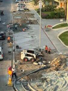 Construction workers in an urban street laying pavement and curbs, highlighting ongoing infrastructure development and urban challenges.