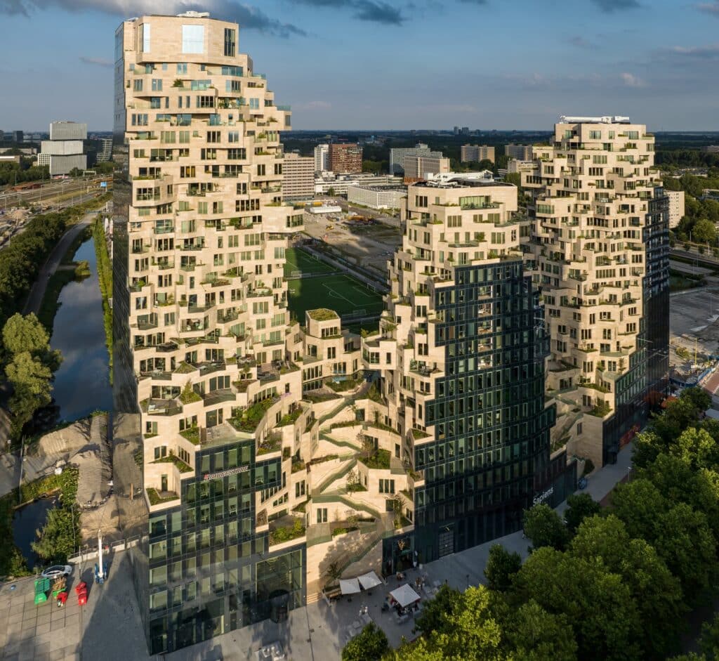 An aerial view of the Valley complex in Amsterdam, showcasing the blend of modern architecture with lush greenery cascading across the terraces.