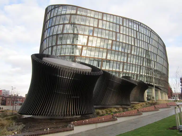 A wide-angle view of One Angel Square in Manchester, showcasing its curved glass façade and modern sustainable architecture.