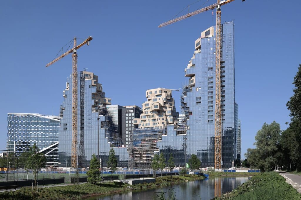 The Valley complex in Amsterdam under construction, showcasing its unique terraced design and reflective glass fa&ccedil;ade.