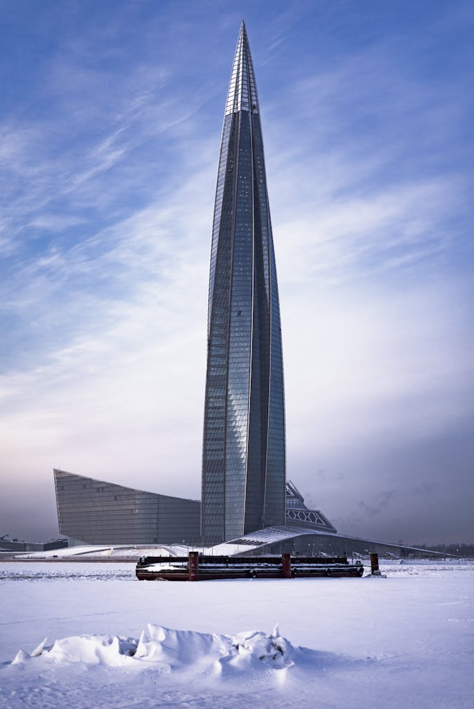 A striking shot of the Lakhta Center skyscraper amidst a snowy landscape, under a clear blue sky.