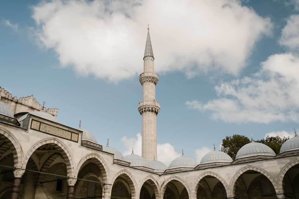 A stunning view of a mosque minaret and arches under a blue sky in Istanbul, Turkey.