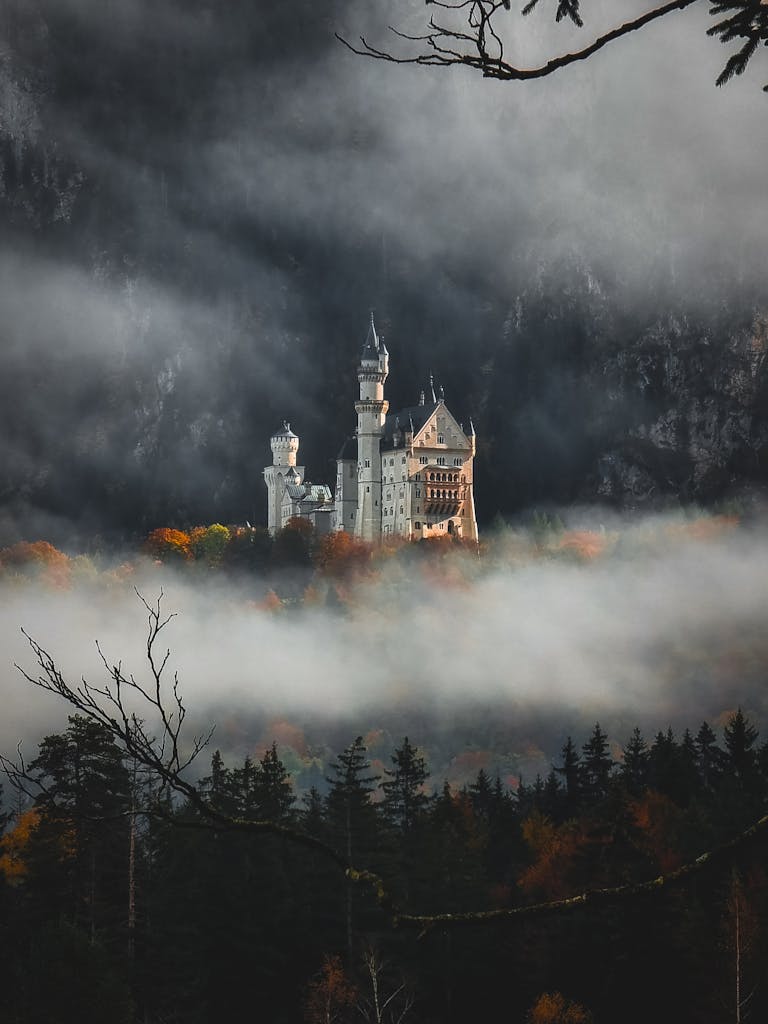 A stunning view of Neuschwanstein Castle surrounded by autumn mist in Schwangau, Germany.