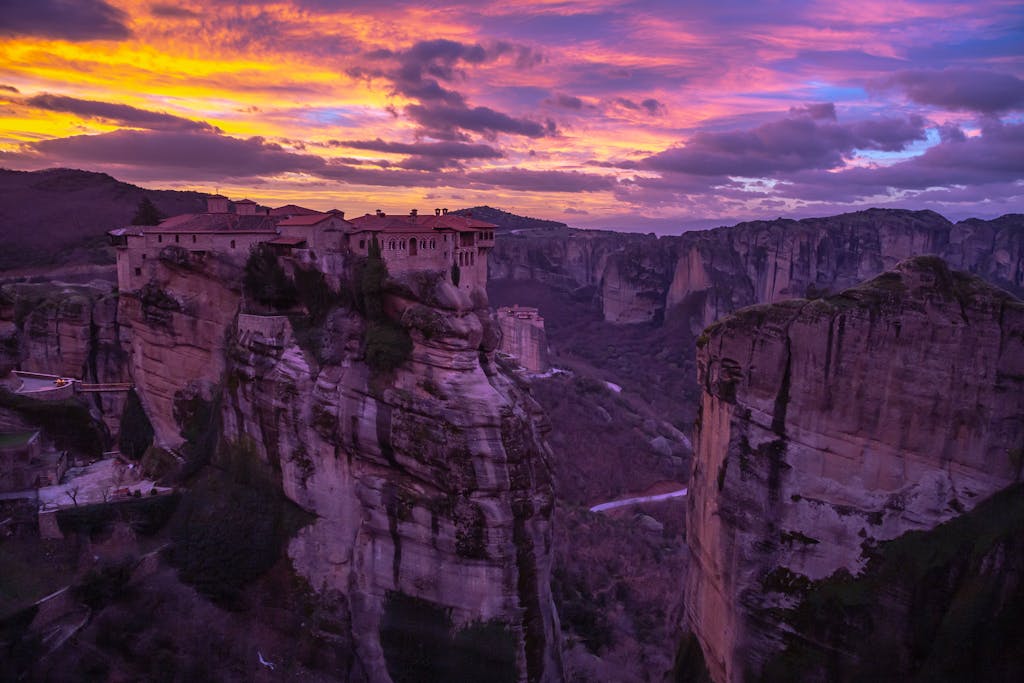 Breathtaking view of Meteora Monastery in Kalabaka, Greece during a vibrant sunset.
