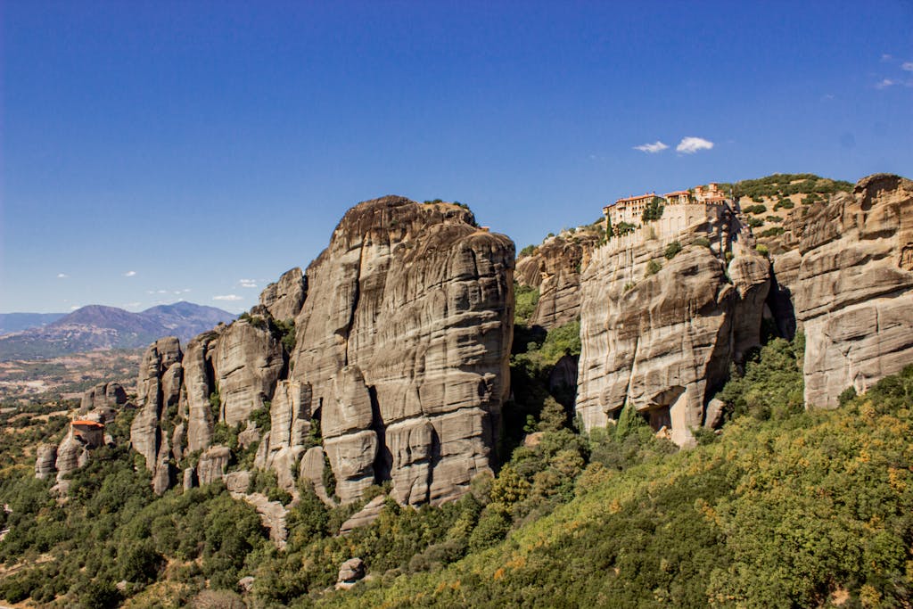 Breathtaking view of the Meteora rock formations and ancient monasteries in Greece under a clear blue sky.