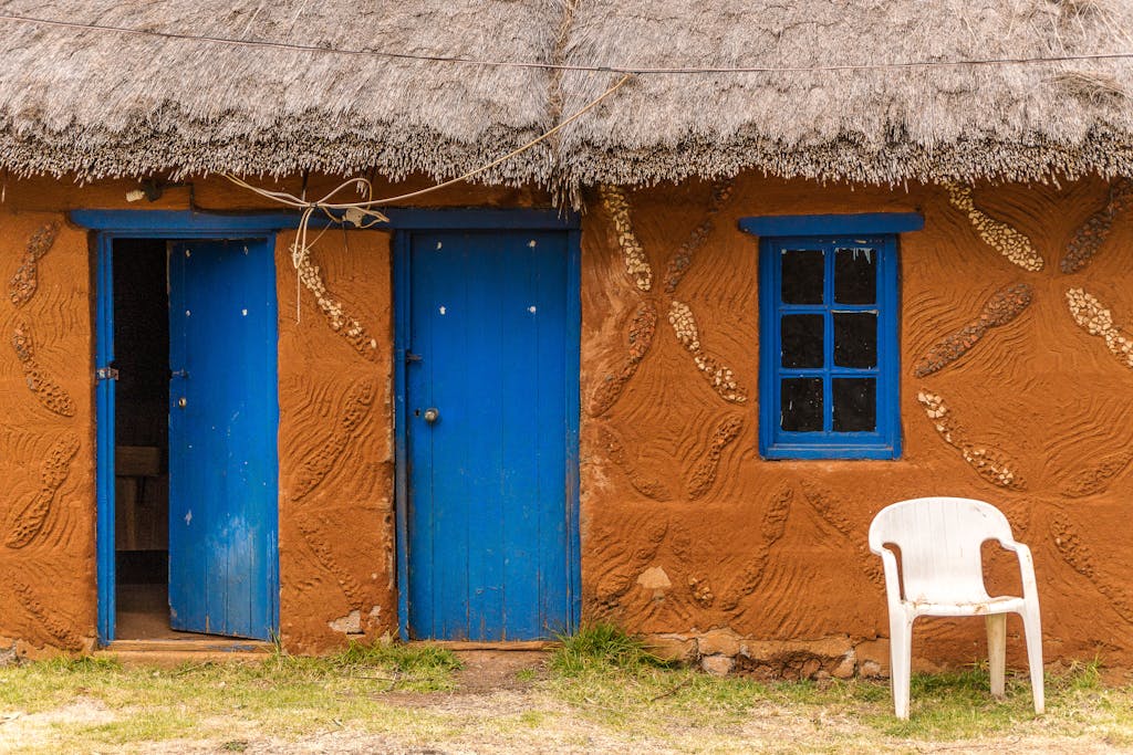 Charming rustic thatched hut featuring vivid blue doors and windows, showcasing cultural architecture.