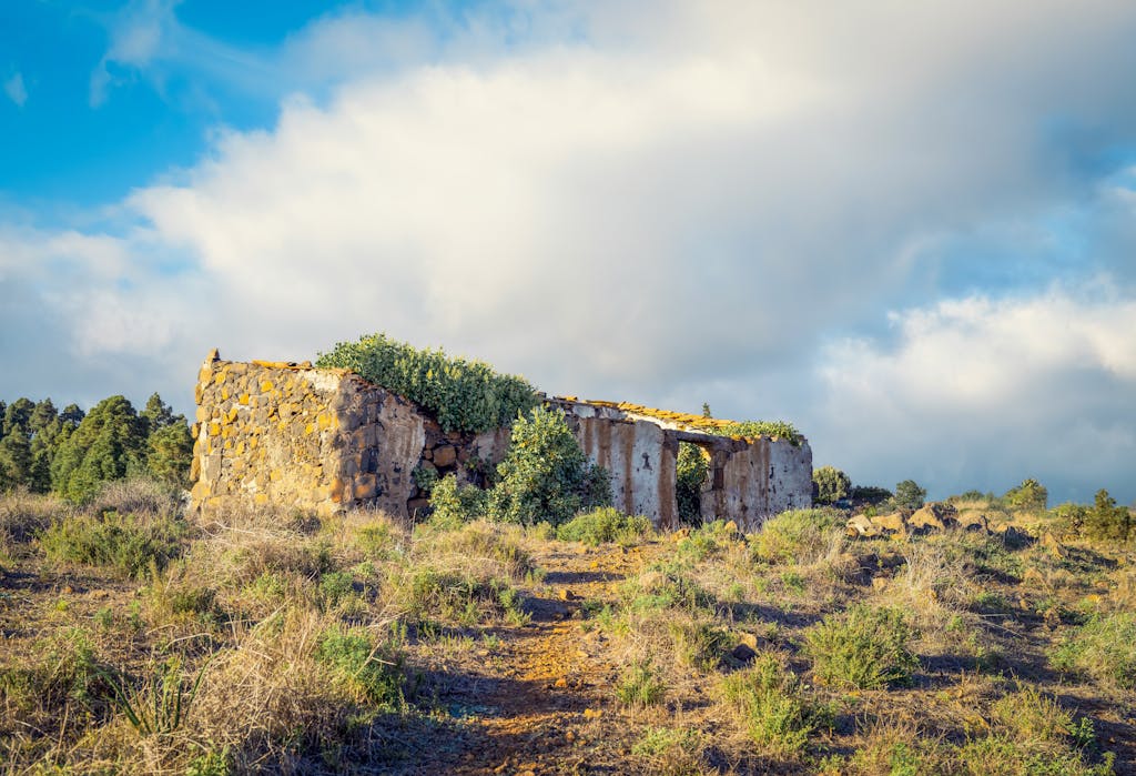 Discover the beauty of ancient stone ruins amidst a tranquil countryside setting under blue skies.
