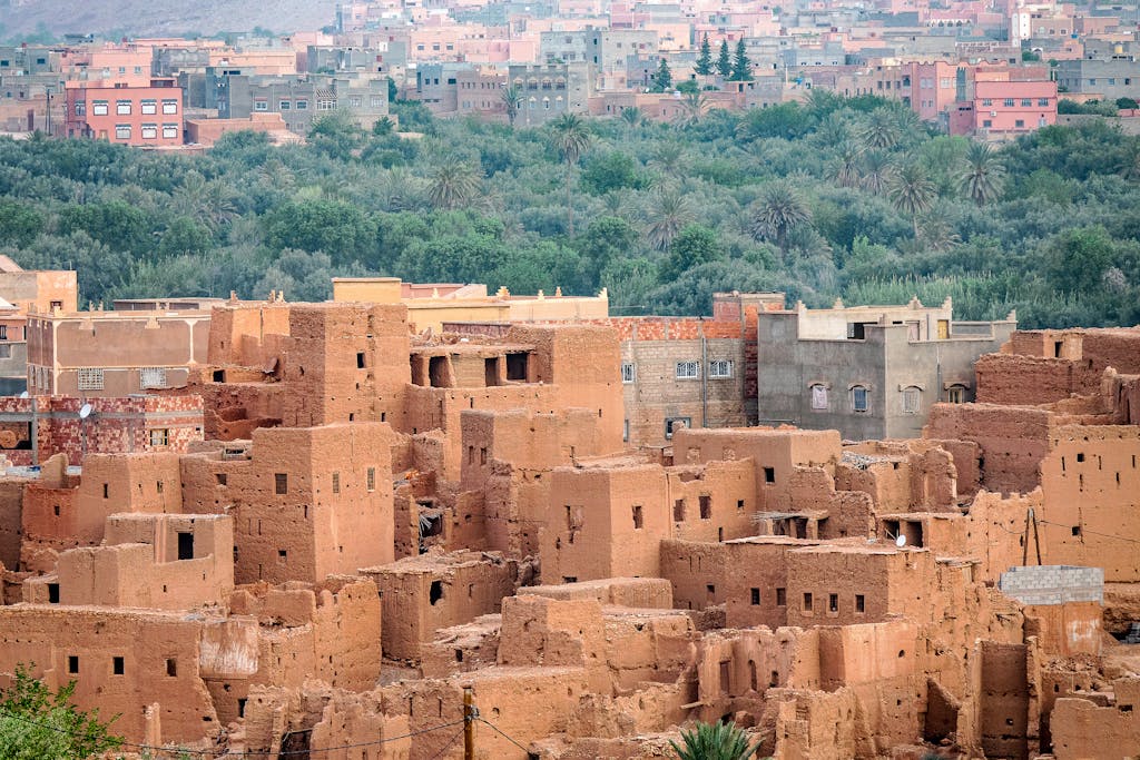 Discover the clay architecture of an ancient Moroccan city with rich greenery in the backdrop.