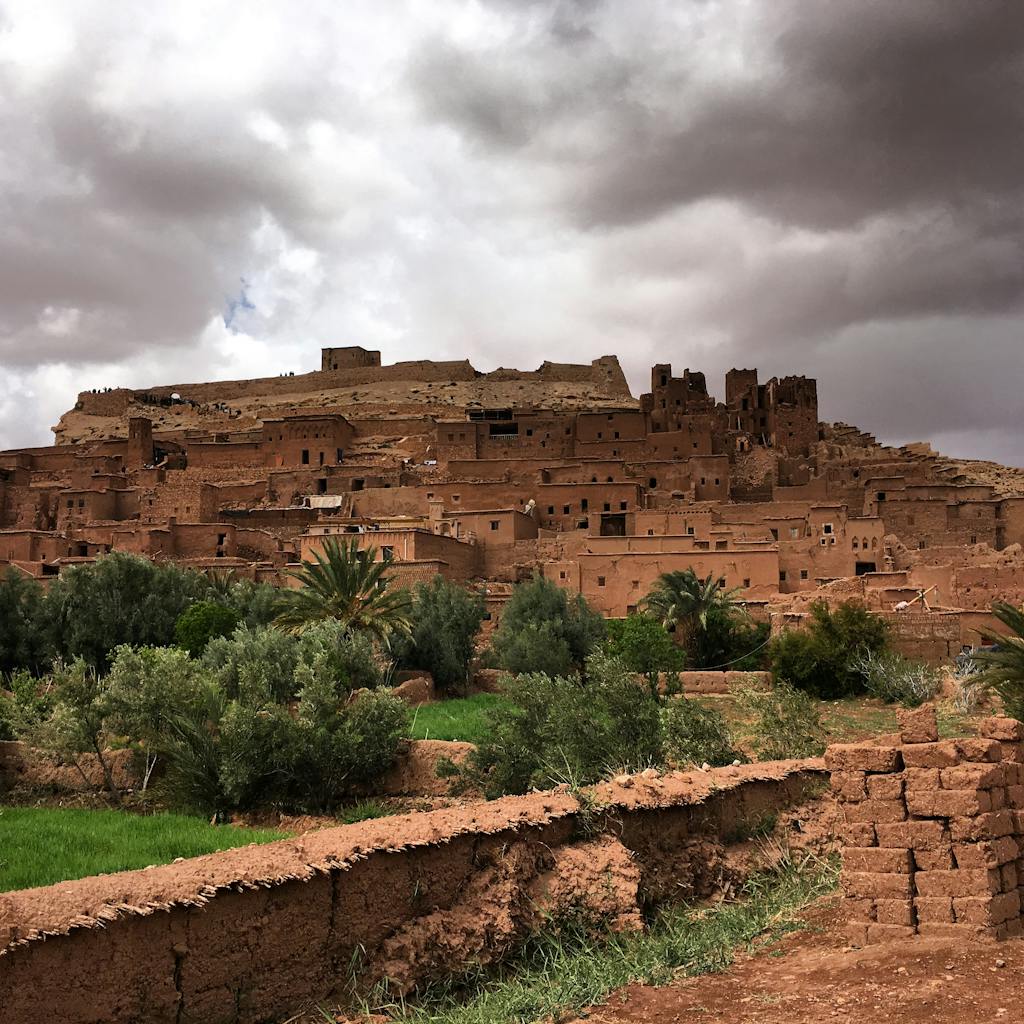 Explore the ancient clay architecture of A&iuml;t Ben Haddou under dramatic skies, a UNESCO World Heritage Site.