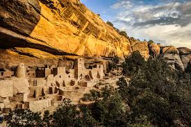 "صورة قصر الجرف (Cliff Palace) أثناء غروب الشمس، يظهر تدرج الألوان على المنحدر الصخري والمباني الحجرية"