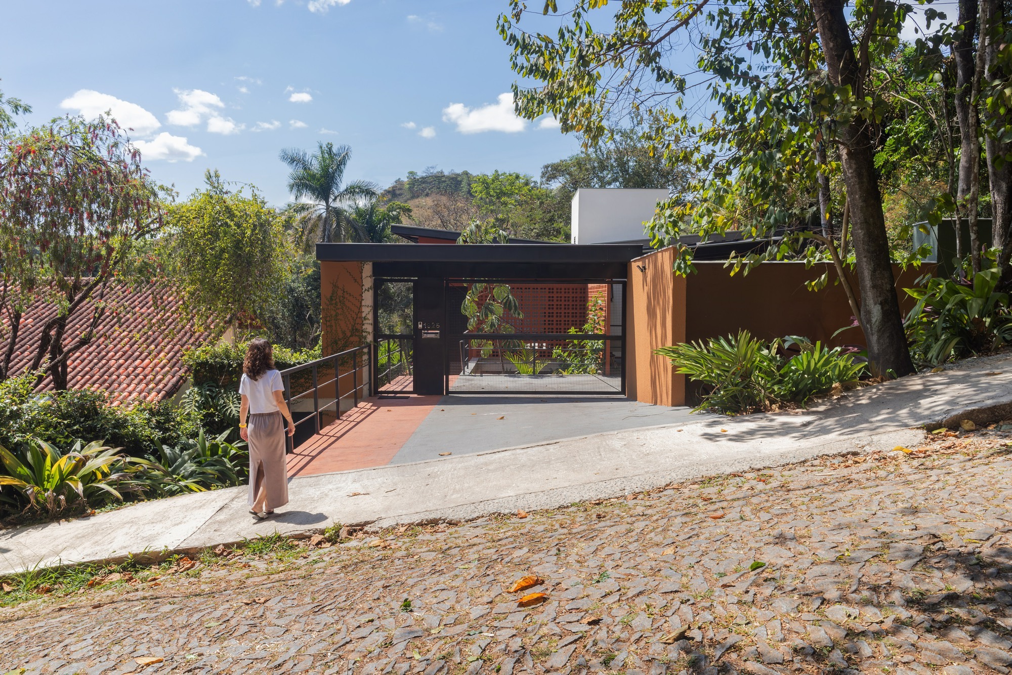 Exterior view of Casa Ouro Velho on a steep slope in Nova Lima showing multi-level architecture integrated with the landscape.