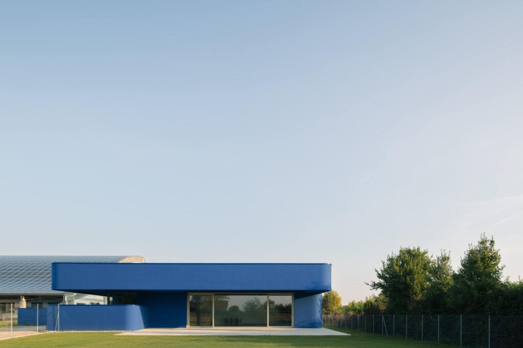 Exterior facade of Noventa Vicentina kindergarten in vibrant blue with angled surfaces creating changing patterns of light and shadow throughout the day.