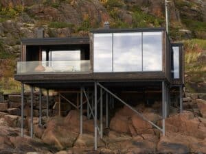 Exterior view of Vipp guesthouse on Storomula island showing wooden stilts and rocky coastline