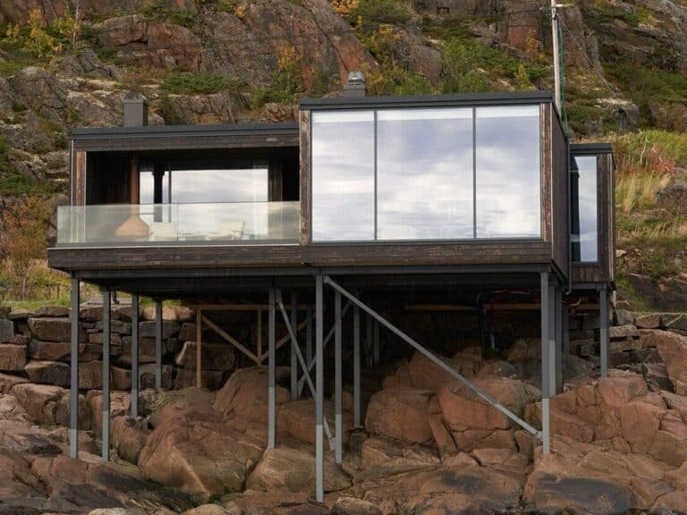 Exterior view of Vipp guesthouse on Storomula island showing wooden stilts and rocky coastline